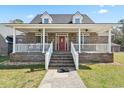 Inviting front porch with white railings and brick steps leading to a red front door on a charming brick house at 450 Deer Spring Loop, Georgetown, SC 29440