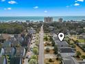 Aerial view of beach neighborhood featuring coastal homes, tree-lined street, and the ocean in the background at 619 10Th Ave. S, North Myrtle Beach, SC 29582