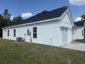 Side view of the home featuring white siding, well-maintained landscaping, and modern exterior lighting at 10534 W Highway 19, Loris, SC 29569
