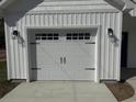 Garage door featuring decorative windows and sleek black hardware, complemented by stylish exterior wall mounted lighting fixtures at 10534 W Highway 19, Loris, SC 29569
