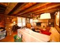 Warm living room showcasing a brick fireplace, beamed ceiling, and wooden walls at 1993 Meadowood Ln., Longs, SC 29568