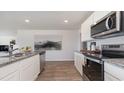 Modern kitchen featuring stainless steel appliances, granite countertops, white cabinets, and hardwood flooring at 234 Bald Cypress Way, Conway, SC 29527