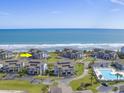 Aerial view of condos by the ocean with a community pool and nicely landscaped grounds under a blue sky at 701 Norris Dr., Pawleys Island, SC 29585
