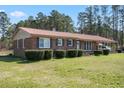 Brick home with a metal roof, well-manicured landscaping and a covered carport at 77 Towhee St., Georgetown, SC 29440