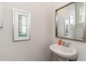 Elegant powder room with pedestal sink, modern mirror, and decorative artwork at 8081 Bear Claw Way, Conway, SC 29526