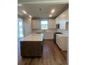 Modern kitchen with white cabinets, stainless steel appliances, and a large island with quartz countertops at 1226 Crested Iris Way, North Myrtle Beach, SC 29582