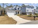 Beautiful two-story home with light gray siding, lush landscaping, and a spacious driveway leading to a garage at 626 5Th Ave. S, Surfside Beach, SC 29575