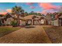 Charming brick home with a well-manicured lawn, large driveway and mature landscaping at sunset at 129 Waterfall Circle, Little River, SC 29566