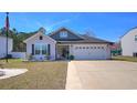 Charming single-story home with well-manicured landscaping, two-car garage and walkway to the front door at 134 Winding Path Dr., Loris, SC 29569