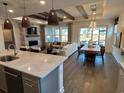 Open-concept living and dining area with kitchen island, fireplace, and outdoor view through large windows at 2534 Watershed Way, Longs, SC 29568