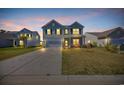 Exterior front elevation of a two-story home with a well-lit lawn at dusk at 3304 Candytuft Dr., Conway, SC 29526