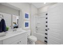 Bright bathroom showcasing a white vanity, toilet, bathtub with a shower, and coastal decor at 3317 Sw Wood Stork Dr., Ocean Isle Beach, NC 28469