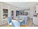 Sunlit dining area with blue upholstered chairs and views to the kitchen and outdoors at 3317 Sw Wood Stork Dr., Ocean Isle Beach, NC 28469