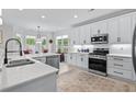 Bright kitchen with white cabinets, stainless steel appliances, an island with bar seating, and light hardwood floors at 870 Monterrosa Dr., Myrtle Beach, SC 29572