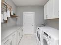 Well-organized laundry room with white cabinets, folding rack, and modern washer and dryer at 9505 Long Meadow Way, Longs, SC 29568