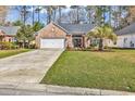 Charming brick home features a well-manicured lawn and a two-car garage, blending comfort with curb appeal at 1151 N Blackmoor Dr., Murrells Inlet, SC 29576