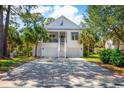 Inviting two-story coastal home featuring a double garage, staircase, and lush landscaping at 208 Summer Wind Loop, Murrells Inlet, SC 29576