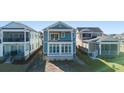 Rear exterior of beautiful blue home showing patio with large windows to let in natural light at 921 Crystal Water Way, Myrtle Beach, SC 29579