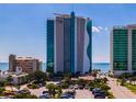 Condo complex exterior showcasing the building's design and proximity to the ocean, blue sky and parking at 107 S Ocean Blvd. # 704, Myrtle Beach, SC 29577