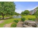 Community pond and fountain surrounded by green grass and trees near condo buildings at 3927 Gladiola Ct. # 101, Myrtle Beach, SC 29588