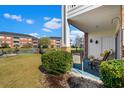 Porch with seating overlooks lush green lawn, pond, and other condo buildings at 3927 Gladiola Ct. # 101, Myrtle Beach, SC 29588