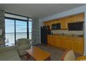 Condo kitchenette with wooden cabinets, black appliances, and access to balcony with ocean view at 4800 S Ocean Blvd. # 1418, North Myrtle Beach, SC 29582
