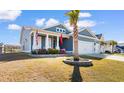 Inviting exterior featuring a well-maintained lawn, palm tree, and a charming front porch with flags at 900 Pelagic Loop, Myrtle Beach, SC 29579