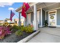 Inviting porch with flags, plants, decorative flowers, and a charming front door with a wreath at 900 Pelagic Loop, Myrtle Beach, SC 29579