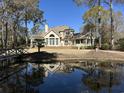 Stunning backyard with pond, bridge, mature trees and a deck, perfect for outdoor entertaining and relaxation at 1599 Hawthorn Dr., Pawleys Island, SC 29585