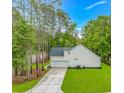 Side view of a white home with a long driveway surrounded by tall trees and a green lawn at 19 Coventry Pl., Pawleys Island, SC 29585