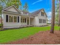 Charming white home showcasing manicured lawn with garden beds and a welcoming entrance at 19 Coventry Pl., Pawleys Island, SC 29585