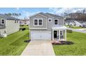 Inviting two-story home featuring a well-maintained lawn, covered porch, and an attached two car garage at 204 Leaflet Loop, Pawleys Island, SC 29585