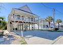 Two-story stilt house with double front porch and paved driveway on a sunny day at 209 30Th Ave. N, North Myrtle Beach, SC 29582