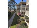 Multi-story condo with multiple balconies, and grassy lawn with mature trees and shrubs at 4242 Pinehurst Circle # N4, Little River, SC 29566