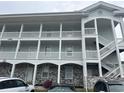 Building exterior featuring light-blue siding, gray-brick accents, and white-columned balconies at 4639 Wild Iris Dr. # 43-204, Myrtle Beach, SC 29577