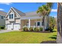 Beautiful home showcasing a charming front porch, well-maintained lawn, and a spacious two-car garage at 1127 East Isle Of Palms Ave., Myrtle Beach, SC 29579