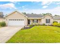 Inviting one-story home with green lawn, complemented by blossoming plants and a spacious two-car garage at 221 Black Bear Rd., Myrtle Beach, SC 29588