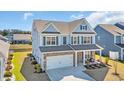Aerial view of a blue two-story home with a two car garage, beautiful front porch, and a well-manicured front lawn at 2825 Stellar Loop, Myrtle Beach, SC 29577