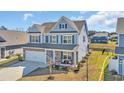 Aerial view of a blue two-story home with a two car garage, beautiful front porch, and a well-manicured front lawn at 2825 Stellar Loop, Myrtle Beach, SC 29577