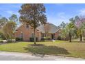Beautiful brick home featuring a well-manicured lawn, lush trees, and classic architectural details at 4222 Congressional Dr., Myrtle Beach, SC 29579