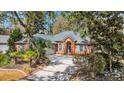Beautifully landscaped brick home featuring a circular driveway and mature palm trees at 74 Dornoch Dr., Pawleys Island, SC 29585
