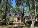 Charming home nestled amongst mature trees, featuring a brick walkway and dormer windows at 133 Otter Run Rd., Pawleys Island, SC 29585