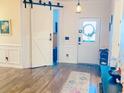 Welcoming entryway with a barn door, hardwood floors, and a decorative wreath on the front door at 256 Copper Leaf Dr., Myrtle Beach, SC 29588