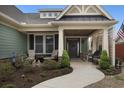 Inviting front porch with seating, a dark wood door, and manicured landscaping at 4228 Ravenwood Dr., Little River, SC 29566