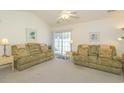 Cozy living room featuring plush sofas, ceiling fan, and sliding glass door access to outdoor living area at 4329 River Gate Ln., Little River, SC 29566