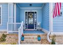 Inviting front porch with rocking chairs, brick steps, blue painted floors and front door with a wreath at 6004 Flowerdale Ct., Myrtle Beach, SC 29579
