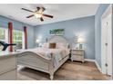 Inviting bedroom with soothing blue walls, ceiling fan, and natural light from the window at 329 Lake Mist Ct., Longs, SC 29568