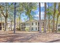 Rear exterior view of a condo with screened porches surrounded by mature trees at 95 Weehawka Way # 2, Pawleys Island, SC 29585