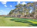 Scenic golf course view with mature trees lining the fairway and condos in the background at 95 Weehawka Way # 2, Pawleys Island, SC 29585