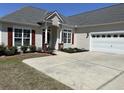 Home featuring a long driveway and garage; complemented by landscaping and dark-red shutters at 59 Willowbend Dr., Murrells Inlet, SC 29576